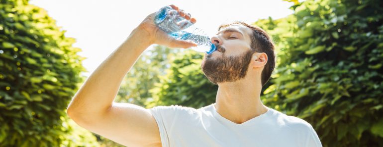 Close up of a man drinking water from a bottle outside