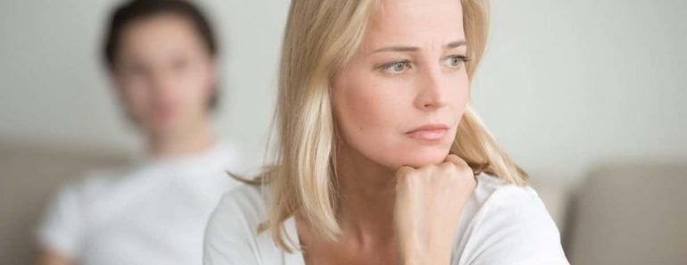 Serious sad woman thinking over a problem, man sitting aside, end of long-term relations, an alcoholic, drug addicted partner, poor conflict management skill, ongoing disagreements with adult son