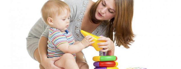 baby boy and mother playing together with construction set toy handing toy to mother