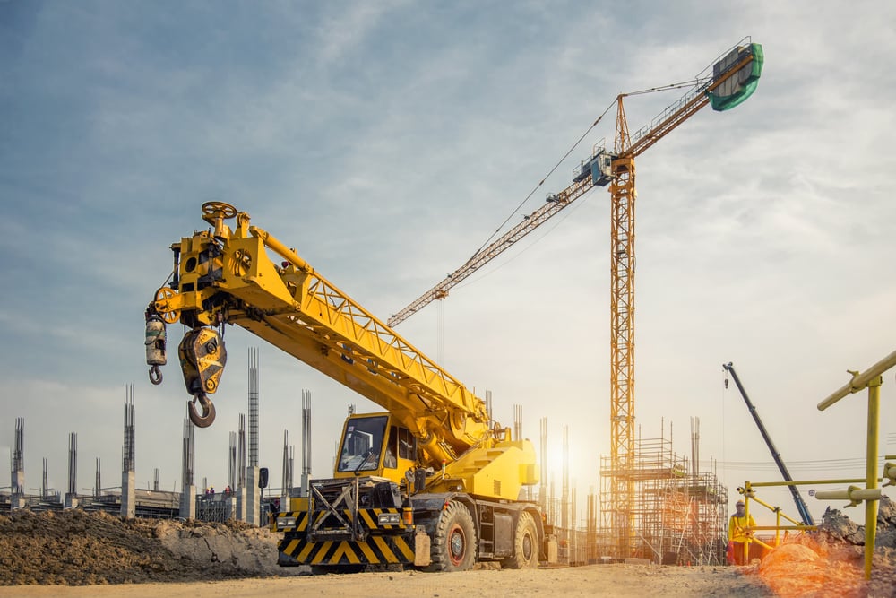 Mobilkran auf einer Straße und Turmdrehkran auf einer Baustelle (Bannafarsai_Stock) s